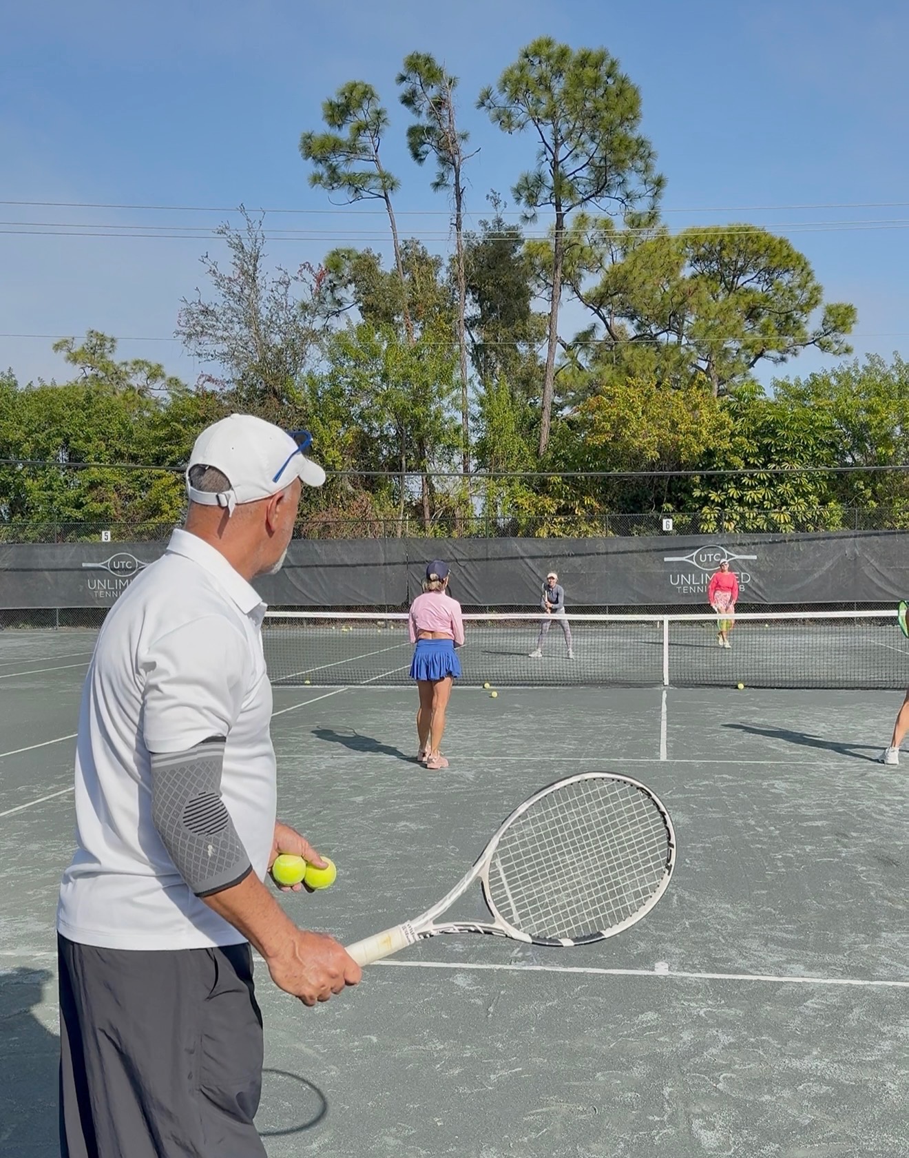 Unlimited Tennis Club player serving during a private lesson on a Har-Tru court in Fort Myers