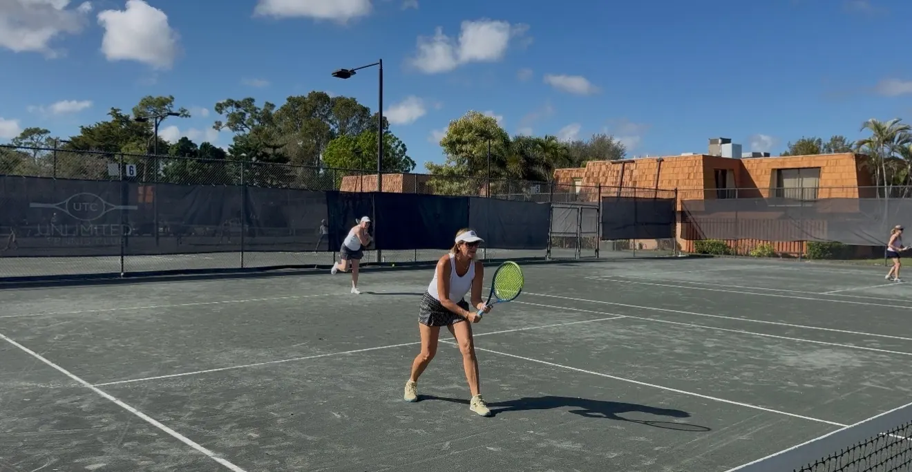 Two Unlimited Tennis Club players celebrating at the net on a Har-Tru court in Fort Myers